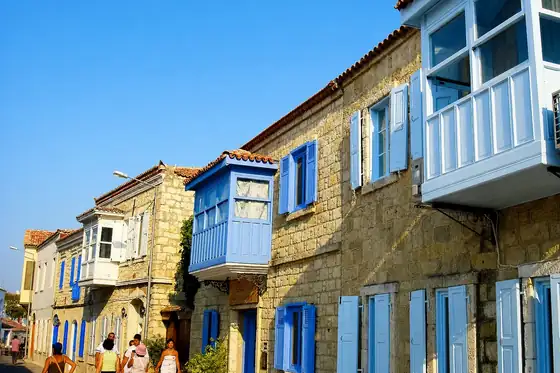 Alaçatı w Alacati: kamienne domy z niebieskimi okiennicami i ludzie na ulicy