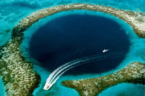 Blue Hole w Dahabie z lotu ptaka: ciemny krąg wody, rafa i łódź na turkusowym morzu