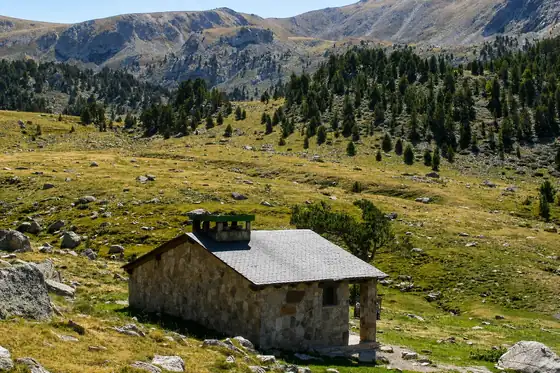 Dolina Madriu-Perafita-Claror w Andorze z kamiennym schronem na łące i stokami gór