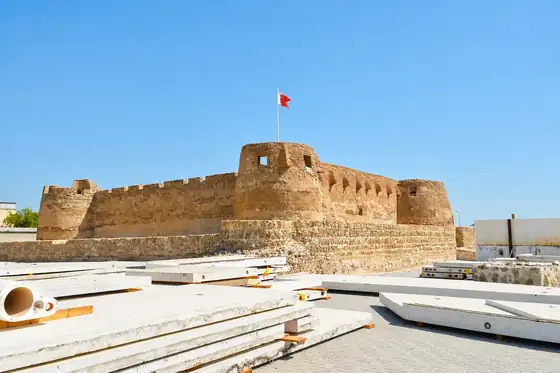 Fort Bahrajnu w Manamie z flagą na murach i elementami kamiennych płyt na pierwszym planie