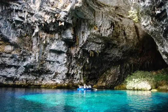 Jaskinia Melissani w Sami, skalne ściany nad turkusową wodą i mała łódź z ludźmi