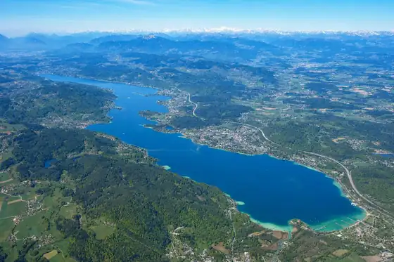 Jezioro Wörthersee w Velden widziane z lotu ptaka, z linią brzegową i górami w tle.