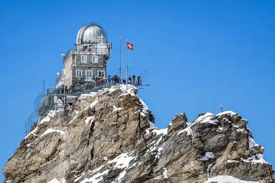 Jungfraujoch w Grindelwald na skalistym szczycie z kopułą i szwajcarską flagą