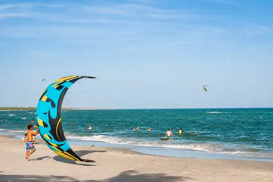 Kitesurfing przy Playa El Yaque w El Yaque, latawiec na plaży i ludzie w wodzie