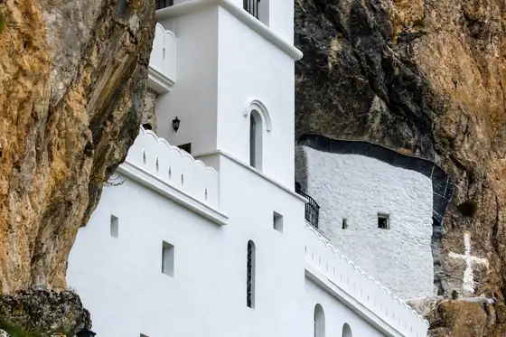 Klasztor Ostrog w Ostrogu, białe budynki w skale i krzyż na ścianie