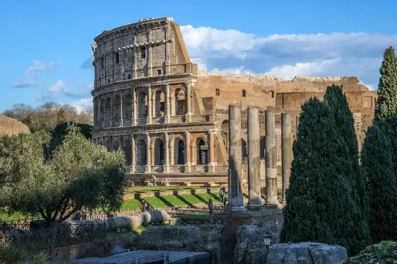 Koloseum i Forum Romanum w Rzymie, widoczne z ruinami kolumn i drzewami.