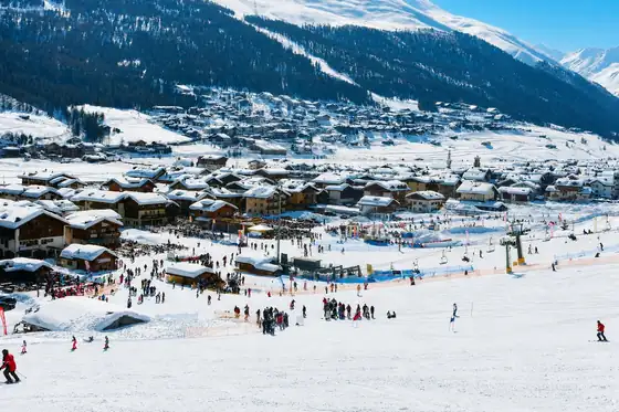 Livigno w Lombardii: ośnieżone stoki, zabudowa miasta i narciarze na trasie