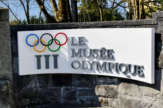 Szyld Muzeum Olimpijskiego w Lozannie przy kamiennym murze