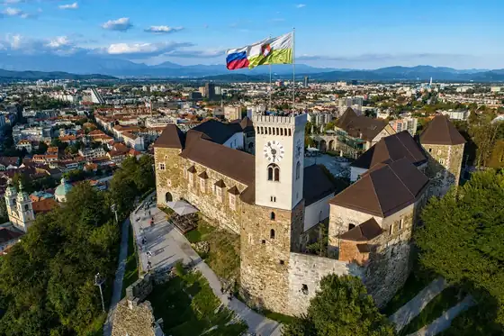 Zamek w Lublanie na wzgórzu z widokiem na miasto i flagami na wieży