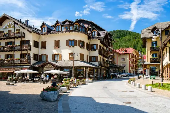 Madonna di Campiglio w Trentino: zabudowa przy ulicy, tarasy i las na wzgórzu