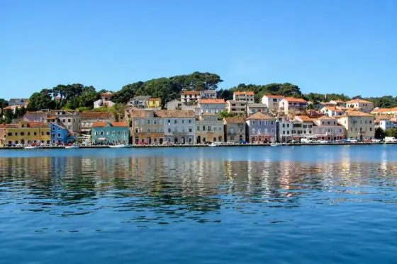 Mali Lošinj i promenada portowa z domami nad brzegiem i odbiciem w wodzie