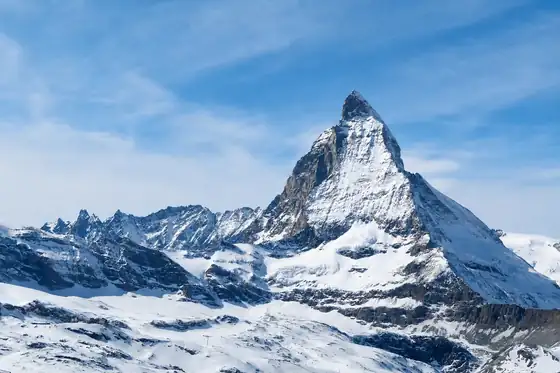 Matterhorn i kolej Gornergrat w Zermatt widziane nad zaśnieżonymi zboczami.