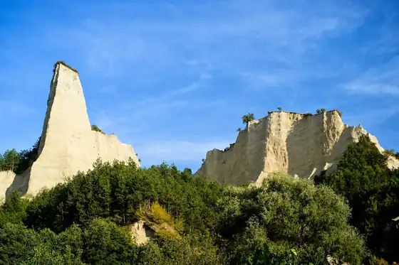 Melnik i Piramidy Melnickie w regionie Pirin, białe skały nad zielonym zboczem.