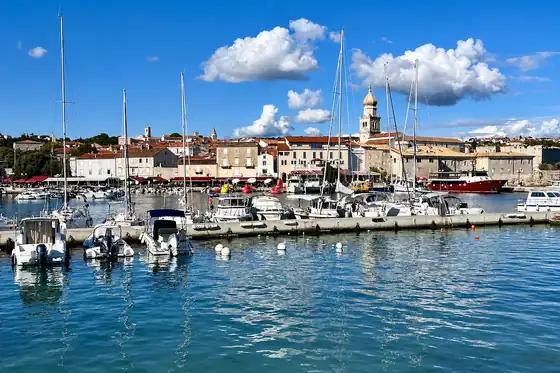 Port w Krku na wyspie Krk z jachtami, łodziami i zabudową przy nabrzeżu