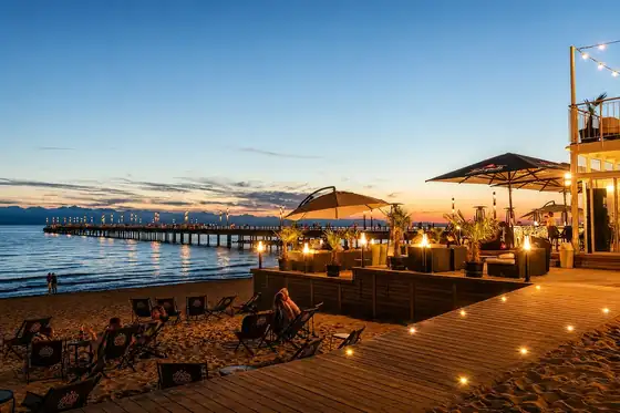 Molo i plaża w Połądze z pomostem nad wodą i leżakami na brzegu