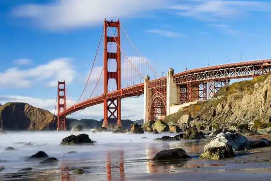 Most Golden Gate w San Francisco nad wodą, z klifami i skałami na pierwszym planie