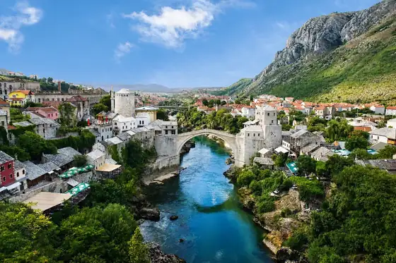 Mostar i Stary Most nad rzeką Neretwą, z zabudową miasta i górami w tle