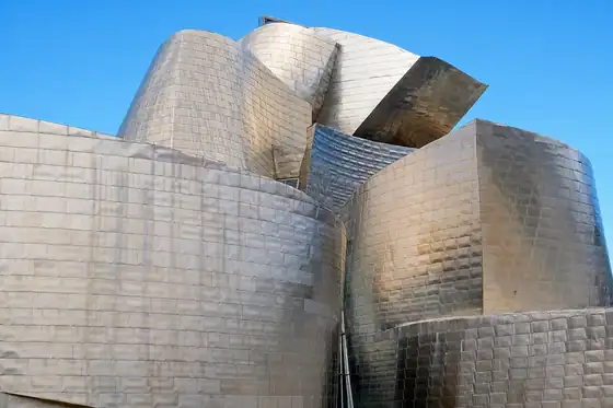 Muzeum Guggenheima w Bilbao z błyszczącą, falującą fasadą przy niebie
