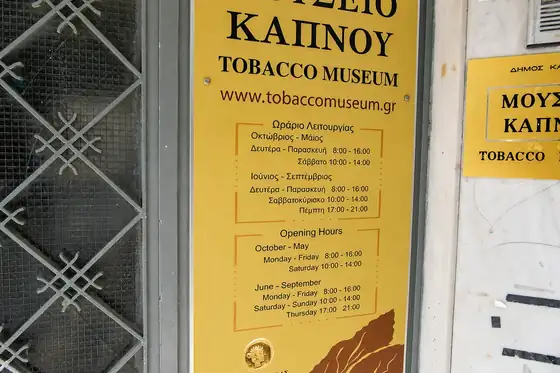 Muzeum Tytoniu w Kawali na żółtej tablicy z godzinami otwarcia przy wejściu