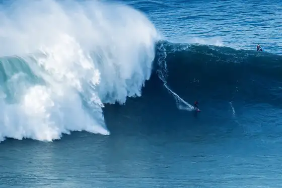 Nazaré i wielkie fale w Nazaré, surfer na wysokiej fali przy brzegu