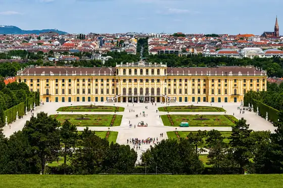 Pałac Schönbrunn w Wiedniu z ogrodami i panoramą miasta w tle.