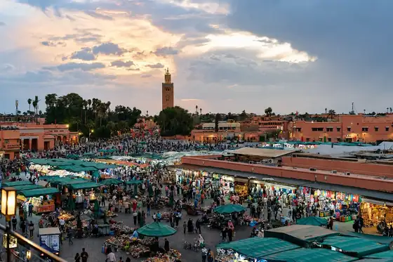 Plac Dżemaa el-Fna w Marrakeszu z tłumem ludzi i straganami pod zielonymi daszkami