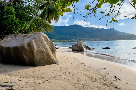 Plaża Beau Vallon w Beau Vallon z piaskiem, głazami, morzem i górami w tle