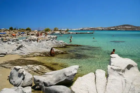 Plaża Kolymbithres w Naoussa, z białymi skałami, piaszczystym brzegiem i ludźmi w wodzie.