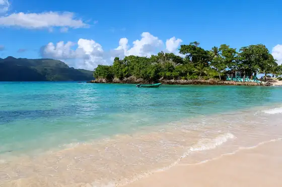 Plaża Playa Rincón w Las Galeras z piaszczystym brzegiem, wodą i łodzią przy brzegu