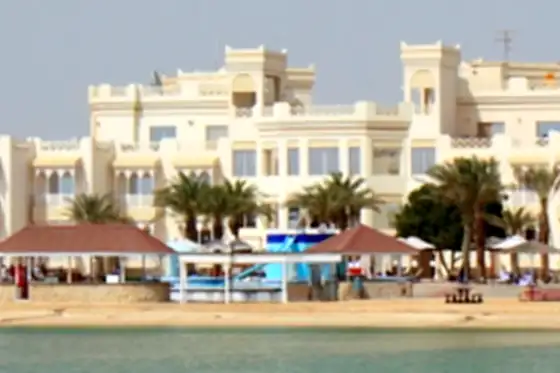 Plaże wyspy Hawar w Bahrajnie z palmami, parasolami i zabudowaniami przy brzegu