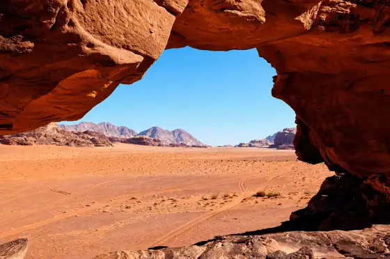 Pustynia Wadi Rum w Jordanii widziana spod skalnego łuku i nad pustynną równiną