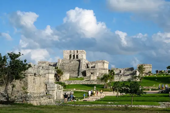 Ruiny Majów w Tulum nad morzem i spacerujący turyści w Meksyku