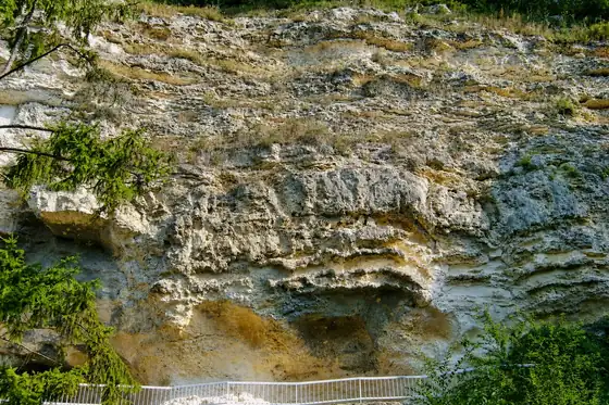 Skalny klasztor Aładża w Złotych Piaskach, wapienna ściana i wejście przy drzewach.