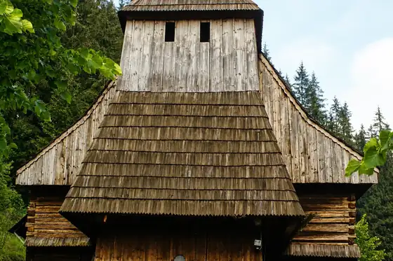 Skansen Orawskiej Wsi w Zubercu, drewniany budynek z wysokim gontowym dachem i wieżą.