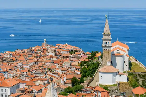 Średniowieczny Piran w Piran z dachami domów, wieżą kościoła i morzem w tle