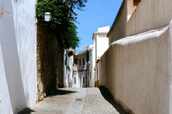 Stare miasto Dalt Vila w Eivissie, wąska brukowana uliczka między białymi murami