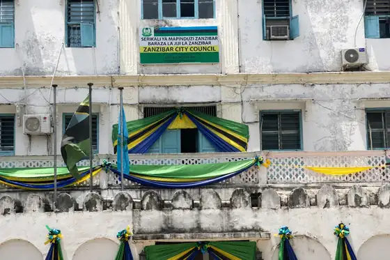 Stone Town w Zanzibarze: biały budynek z niebieskimi okiennicami i flagami przy fasadzie