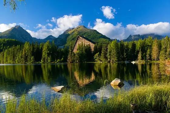 Szczyrbskie Jezioro w Szczyrbskim Plesie nad wodą, z lasem i górami w tle