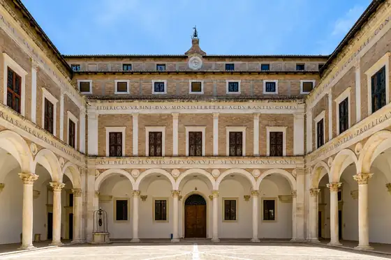 Urbino i Pałac Książęcy: arkadowy dziedziniec z zegarem i kolumnami w Urbino.