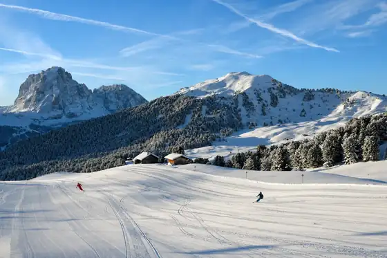 Val Gardena w Ortisei: ośnieżony stok z narciarzami i górami w tle