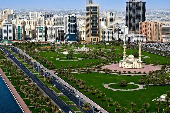 Wielki Meczet Szejka Zajida w Abu Zabi i park z palmami oraz wieżowcami w tle
