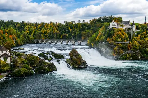 Wodospad Renu w Neuhausen am Rheinfall z mostem i zamkiem nad rzeką.
