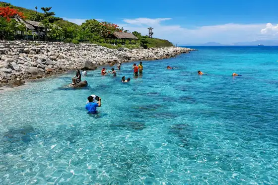 Wyspa Hon Mun i nurkowanie w Nha Trang, ludzie w wodzie przy skalistym brzegu