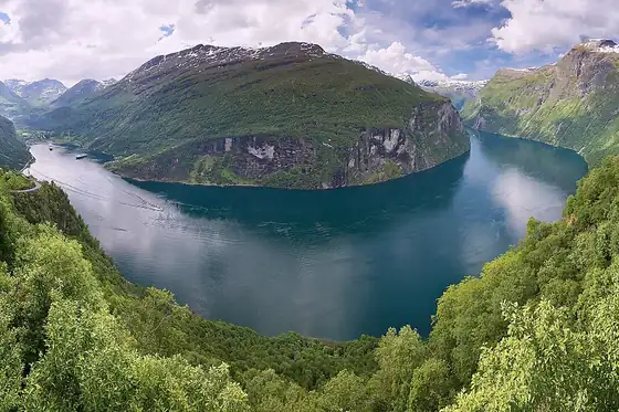 Fiord Geiranger w Norwegii z wodą między stromymi zielonymi zboczami i górami