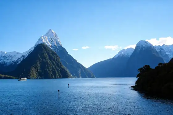 Fiord Milford Sound w Nowej Zelandii z górami, wodą i małą łodzią.