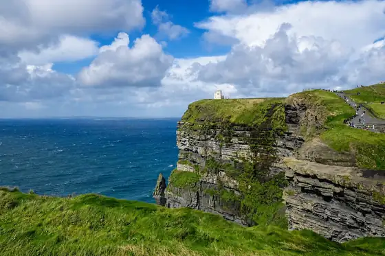 Klify Moheru w Irlandii, strome urwisko nad oceanem i ścieżka na grzbiecie klifu.