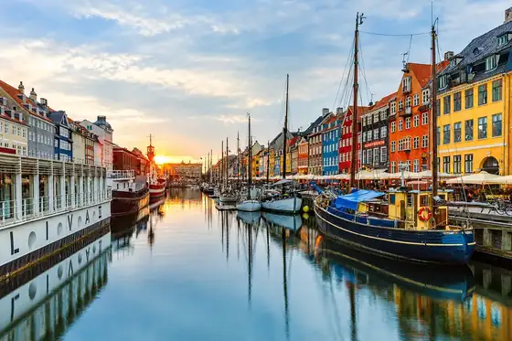 Nabrzeże Nyhavn w Kopenhadze, Dania, z kanałem, łodziami i kolorowymi kamienicami po obu stronach.