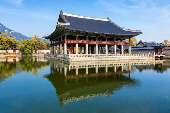 Pałac Gyeongbokgung w Seulu w Korei Południowej odbija się w wodzie obok pawilonu i drzew