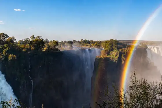 Wodospady Wiktorii w Zimbabwe z kaskadami wody i tęczą nad urwiskiem.
