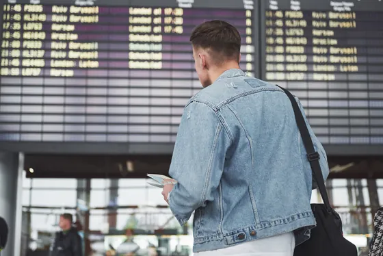 Podróżny przed tablicą odlotów na lotnisku